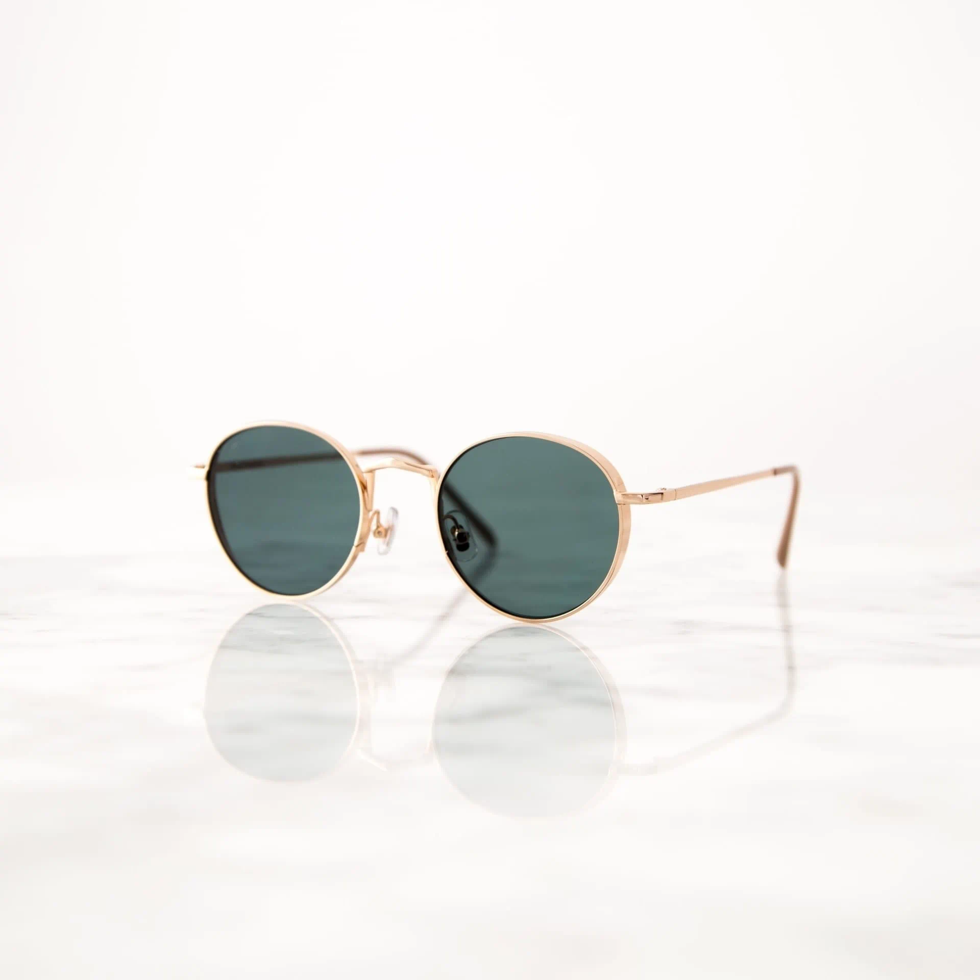 Gold frame sunglasses on reflective marble surface